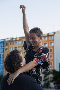 İki genç gelin ve damat, caddedeki bir köprünün korkuluklarında mutlu bir şekilde gülümsüyor.