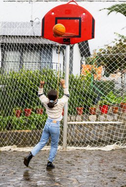 Basketbol oynayan bir kız topu dikey olarak atıyor.