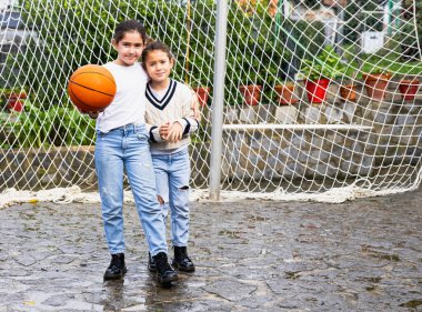 Evde basketbol oynadıktan sonra birbirine sarılan iki kız.