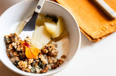 Bir kase sağlıklı yiyecekle yoğurt, meyve ve mısır gevreğinin yakın çekimi.