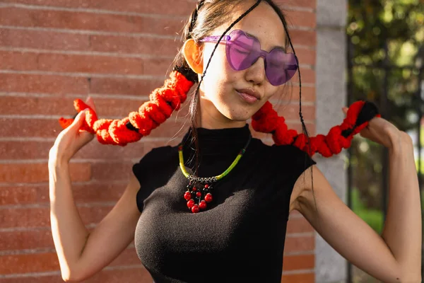 カラーメガネでポーズし 赤い髪の装飾で髪を保持する若いアジアの少女の肖像画 — ストック写真