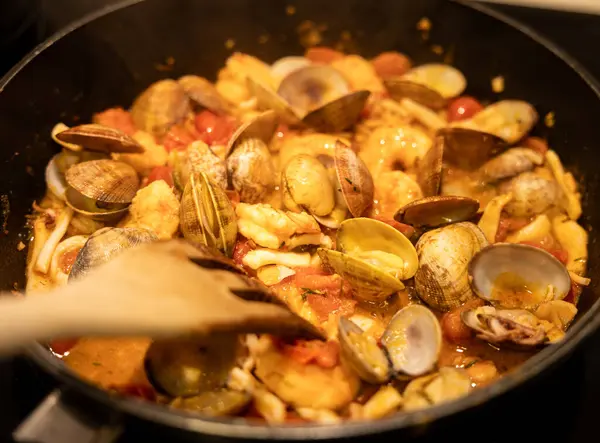 炖菜一种美味的海鲜炖菜 有蛤蟆 虾子和西红柿在一个黑色锅里煮着 — 图库照片