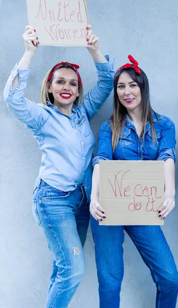 青い服を着た2人の笑顔の女性が 団結と女性のエンパワーメントを示す ユナイテッド ウィメンズ とのサインを掲げる — ストック写真