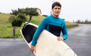 Kendine güvenen sörfçü sörf tahtasıyla sahile gidiyor, sörf seansına hazır..