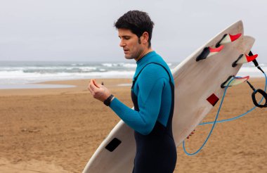 Korunmak için kulak tıkaçlarıyla denize doğru giden sörfçü..