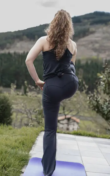 Woman balancing in a yoga posture in the middle of nature, enjoying the view.
