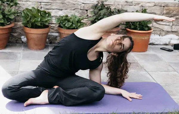 Una Mujer Enfocada Haciendo Estiramiento Lateral Sentado Una Esterilla Yoga Imagen de archivo