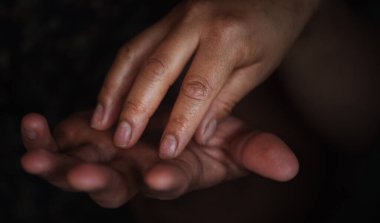 Bir çiftin ellerinin birbirine nazikçe dokunuşunun yakın plan görüntüsü derin bağlarını ve duygusal bağlantılarını simgeliyor..