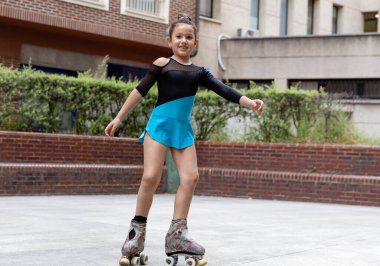 Paten kayarken kameraya gülümseyen genç bir kız, mavi ve siyah bir mayo giyiyor. Neşe kavramı, çocukluk eğlencesi ve aktif oyun.