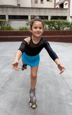 Mavi taytlı genç bir kız kameraya doğru ustalıkla kayarken gülümsüyor ve dışarıda eğleniyor..