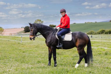 Emekli bir adam kırsalda ata biniyor, güzel kırsal manzaranın ortasında boş zamanlarının ve hobilerinin tadını çıkarıyor..