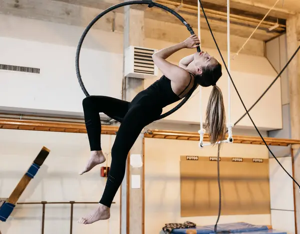 stock image Woman performing an acrobatic exercise on an aerial hoop in a studio, showcasing strength and flexibility.