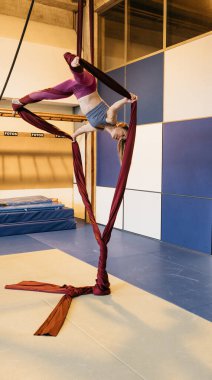 Stüdyoda havadaki ipekler üzerinde ters akrobatik hareketler yapan kadın dayanıklılık, esneklik ve zarafet sergiliyor..