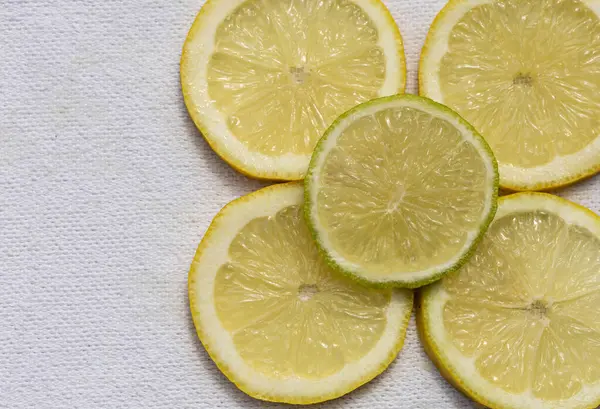 Beyaz arka planda estetik olarak düzenlenmiş limon dilimleri canlı sarı renklerini ve sulu dokularını gözler önüne seriyor..