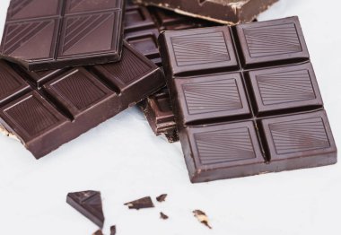 Beyaz arka planda çeşitli siyah çikolatalar var. Yemek, tatlı ve şekerleme temaları için ideal.