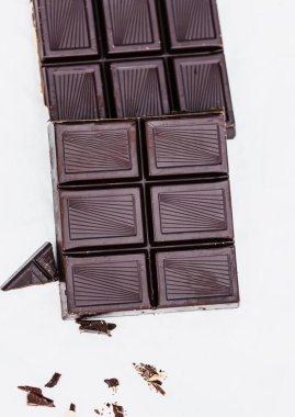 Beyaz arka planda birkaç kırık parçalı koyu çikolataların dikey yakın çekimi. Yemek ve şekerleme temaları için ideal.