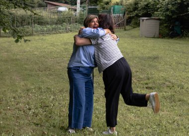 İki arkadaş, yemyeşil bir tarlada arkadaşlıklarını kutlamak için pikniğe geldiklerinde sıcak bir kucaklaşmayı paylaşıyorlar..