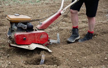 Bahçede traktörle çalışan bir adamın bacaklarının ayrıntıları..