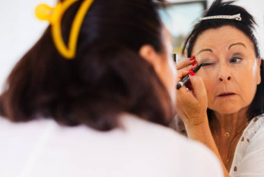 Yaşlı bir kadının dikkatli bir şekilde göz kalemi sürerken yakın plan çekimi.