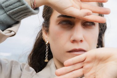 Ellerini kullanarak yüzünü dışarıya kapatan genç bir kadının yakın çekimi..