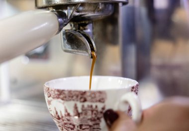 Espresso kahve makinesinden eski bir seramik fincana akıyor.