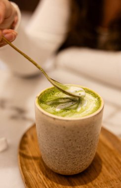 Altın kaşıkla karıştırılan matcha latte 'nin yakın çekimi..