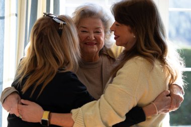 Mutlu yaşlı kadın sıcak ve neşeli bir anda iki arkadaşını kucaklıyor..