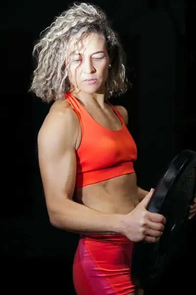 Turuncu kıyafetli sporcu kadın antrenman sırasında tabak tutuyordu.