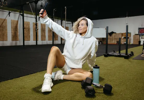 Spor giyim bölümünde formda bir kadın spor molasında selfie çekiyor.