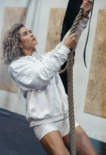 Kapüşonlu atletik kadın. İp tutuyor ve eğitime başlamadan önce yukarı bakıyor.