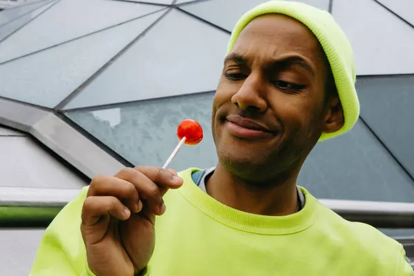 Şehir ortamında kırmızı bir lolipopla eğlenen genç adam