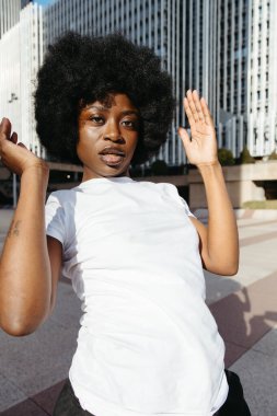 Siyah kadın kameraya bakarken yoğun bir dans gösterisi sergiliyor.