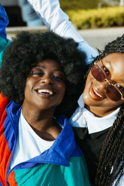 Mutlu Afro arkadaşlar gülümsüyor ve şehirde poz veriyorlar.