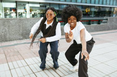 Afro kadınlar şehir sokaklarında neşeyle dans ediyorlar.