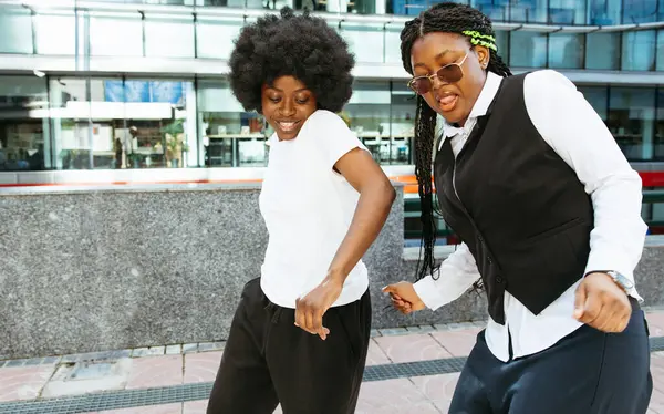 Şehirdeki yüksek binalarla birlikte dans eden Afro arkadaşlar.