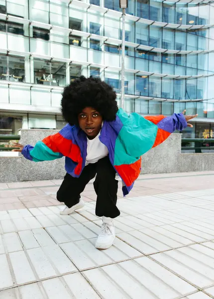 Kendinden emin afro kadın dans ediyor ve kameraya bakıyor.