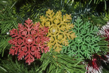 Ağaçta üç renkli kar tanesi var. Yeni yıl ağacında kırmızı sarı ve yeşil kar taneleri. Ağaçtaki süslemeler. Noel ağacı için yeni yıl süslemeleri