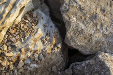 Deniz kıyısında büyük kayalar ve aralarında bir boşluk var. Arkaplanda büyük taşlar