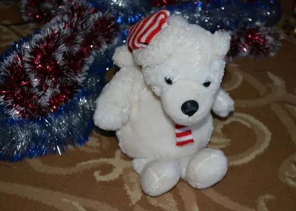White fluffy toy bear surrounded by New Year \'s Eve garlands. New Year\'s Toy Attributes