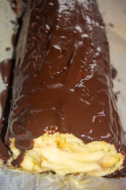 Siyah çikolatayla kaplı muz kremalı sünger rulosu. Bisküvi yuvarlama görünümü bir uçta