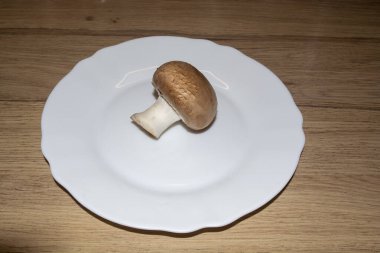 Beyaz tabakta kirli bir mantar şampiyonu. Mantarlı yemek hazırlamak için gerekli malzemeler. Mantar şampiyonu.