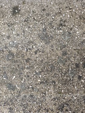 Arka planda küçük beyaz çakıl taşları olan beton bir duvar var. Arka plan koyu gri betondan. Taş arkaplan