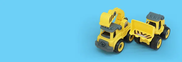 텍스트 배너에 공간이있는 파란색 배경에 노란색 플라스틱 트럭과 불도저 장난감 — 스톡 사진
