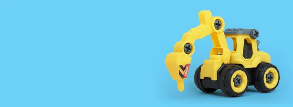 黄色塑料拖拉机钻头玩具 蓝色背景隔离 文本或玩具商店横幅复制空间 — 图库照片