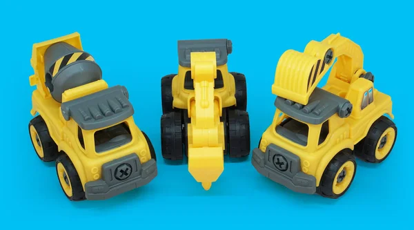 コンクリートミキサー トラクタードリル 掘削機トラックの黄色いプラスチックのおもちゃは 青い背景で隔離されています 重い建設車両 — ストック写真