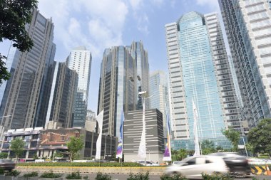 Modern ofis binaları mavi gökyüzüne karşı. Jakarta Endonezya ufuk çizgisi apartman, apartman ve ofis cepheleriyle sokaktan görülüyor.