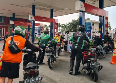 Depok - Indonesia, August 1st 2024: People are queuing to refill their motorbikes with subsidized Pertalite fuel at a gas station in Depok clipart