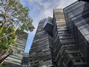 Eşsiz Modern çevre dostu cam mimari cephesi ve mavi gökyüzüne karşı yeşil ağaçlar. Endonezya Üniversitesi bina cephesi.