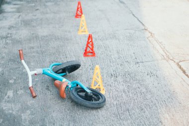 Yeşil Tosca itme motoru ya da dengeli bisiklet ve beton zeminde terk edilmiş eğitim konileri. Toodler için güvenlik bisikleti eğitimi.