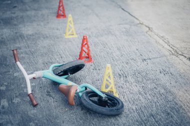 Yeşil Tosca itme motoru ya da dengeli bisiklet ve beton zeminde terk edilmiş eğitim konileri. Toodler için güvenlik bisikleti eğitimi.